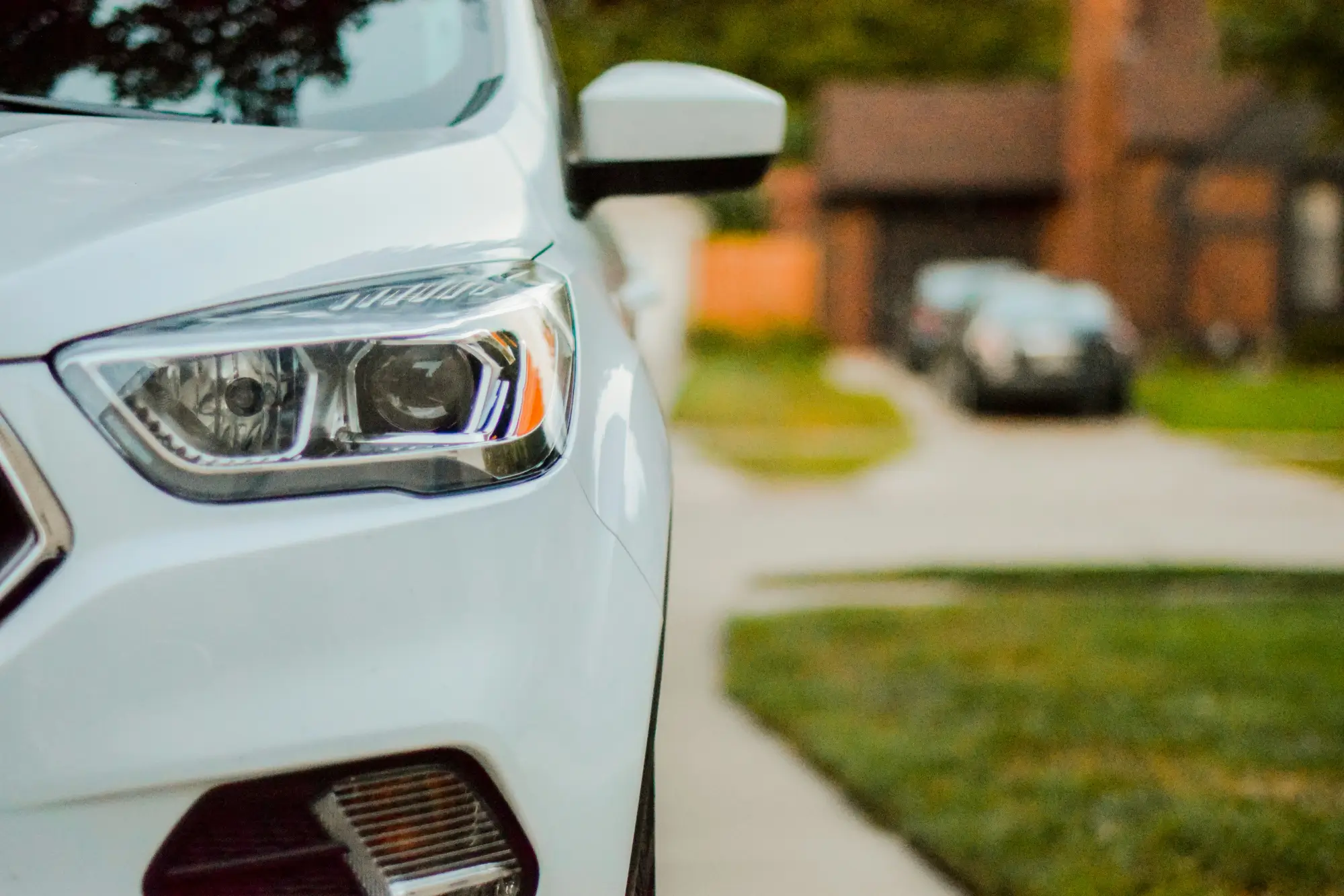 Close-up of a car's headlight and front fender parked in a driveway